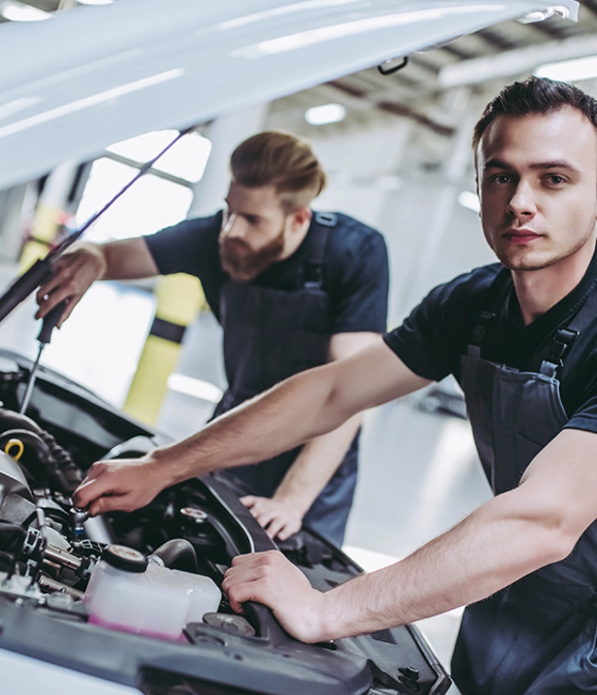 Two men working on a car in an auto shop.