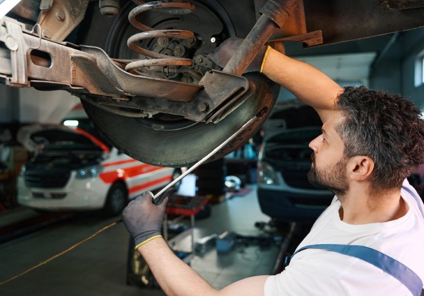 A man working on the underside of an automobile.