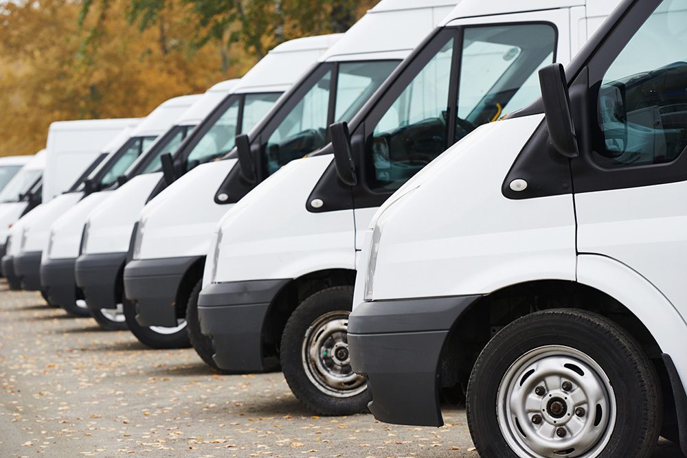 A line of white vans parked in a row.